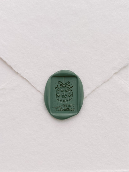 green rectangular Merry Christmas ornament design wax seal on a white envelope