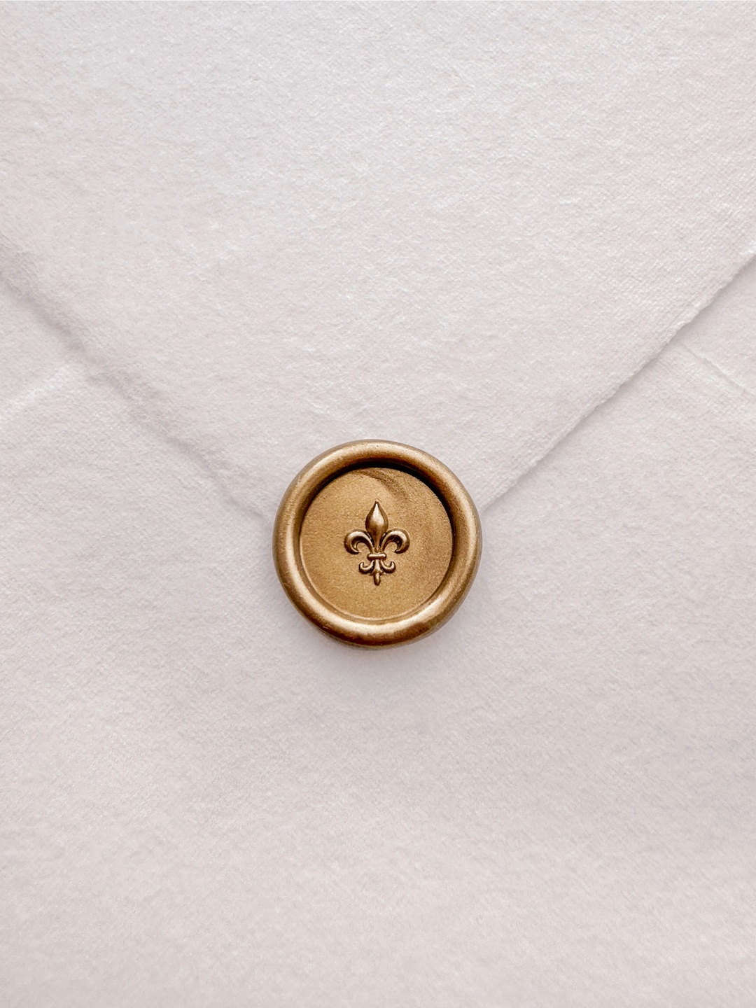 Gold 3D fleur de lis mini wax seal on a white handmade paper envelope
