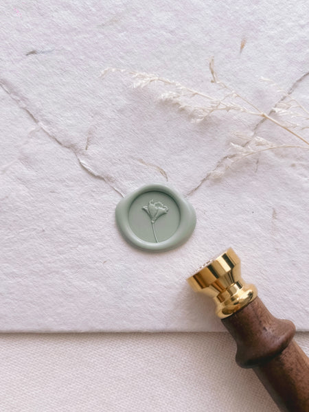 Light green colored 3D flower mini wax seal on a white textured envelope