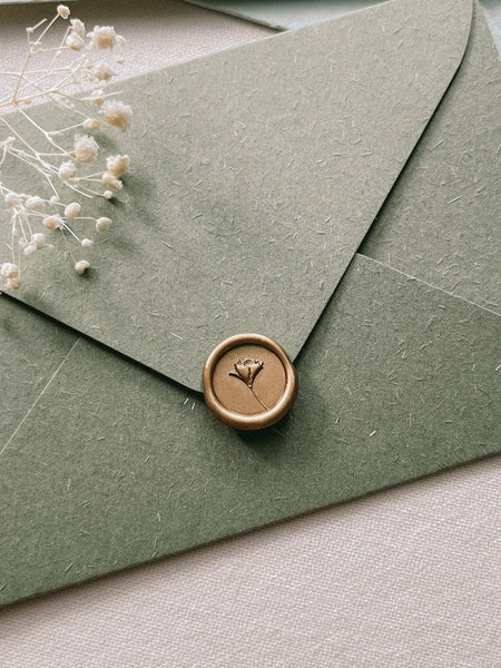 a flower design mini gold wax seal on olive green envelope