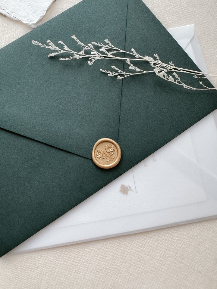 light gold mini flowers wax seal on a dark green envelope 