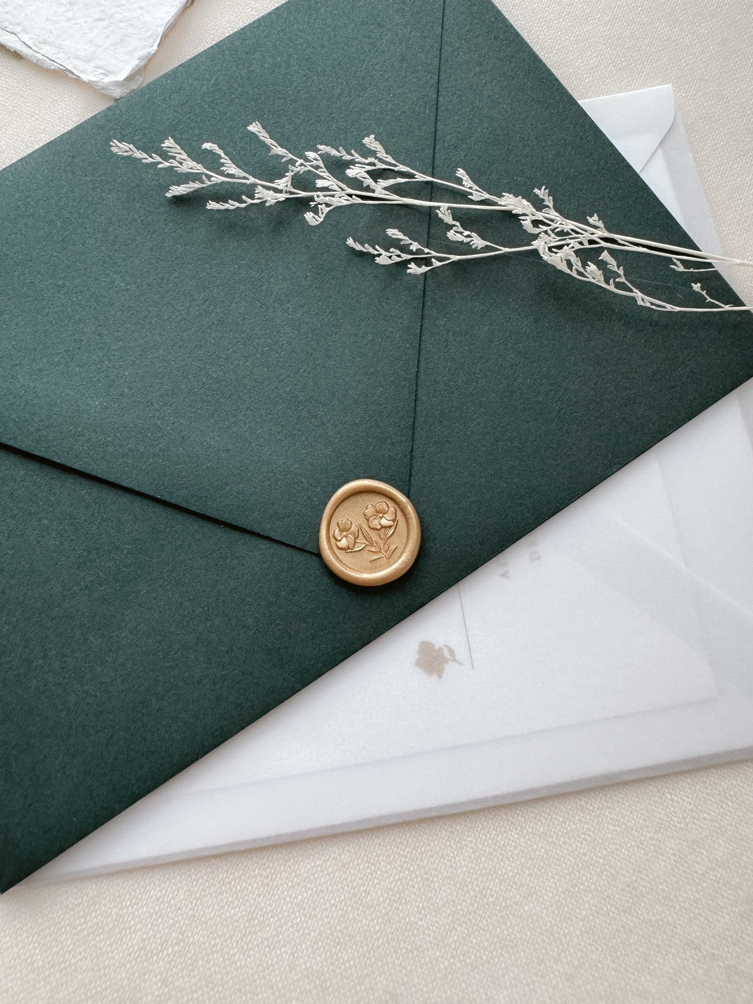 Mini light gold wax seal featuring gardenia flowers with 3D engravings on a dark green envelope