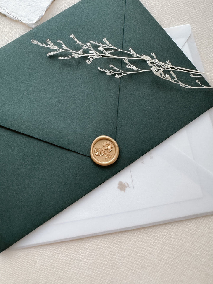 Mini light gold wax seal featuring gardenia flowers with 3D engravings on a dark green envelope