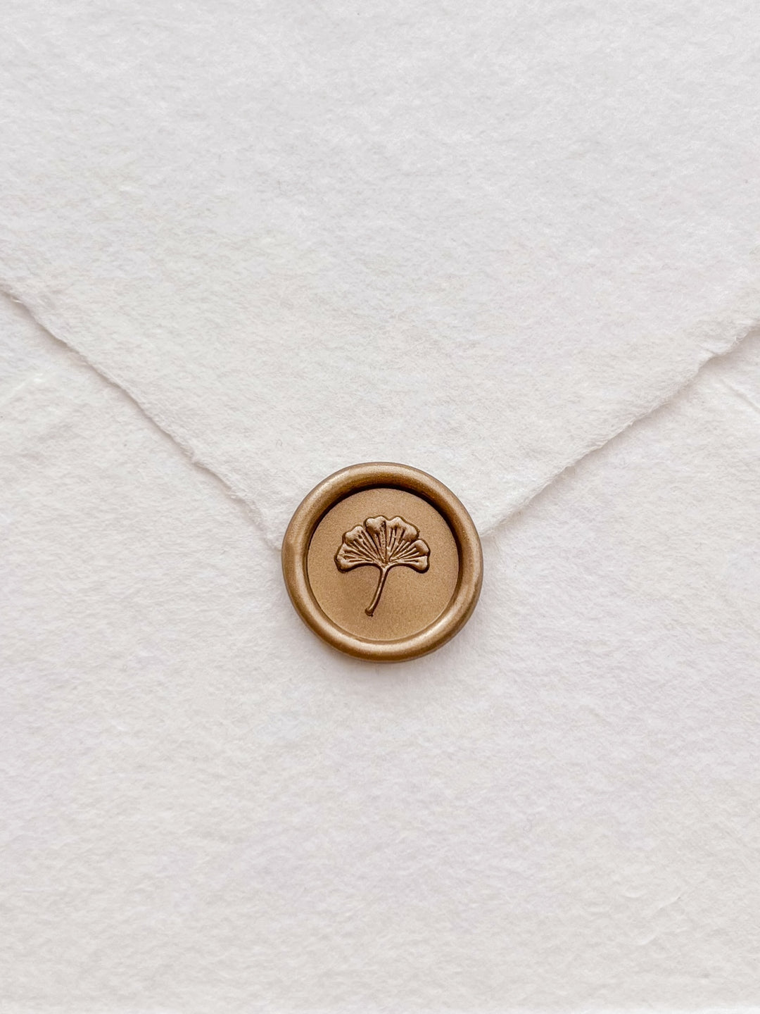 classic gold 3D mini ginkgo wax seal on a white deckle-edge handmade paper wedding envelope flap