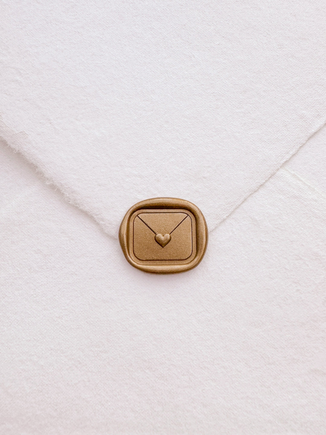 Gold 3D heart sealed envelope love letter wax seal on a white deckle-edge handmade paper envelope