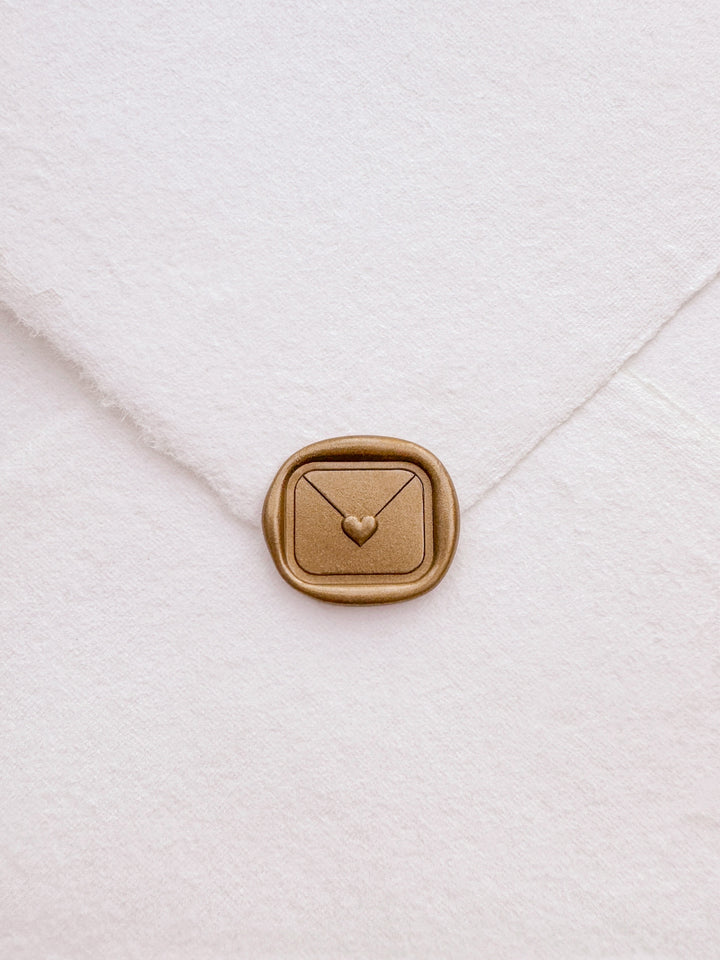 Gold 3D heart sealed envelope love letter wax seal on a white deckle-edge handmade paper envelope