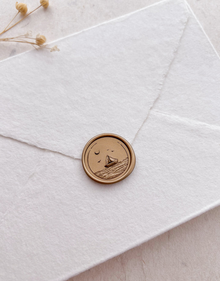Sailboat and ocean waves design gold wax seal on a white envelope 