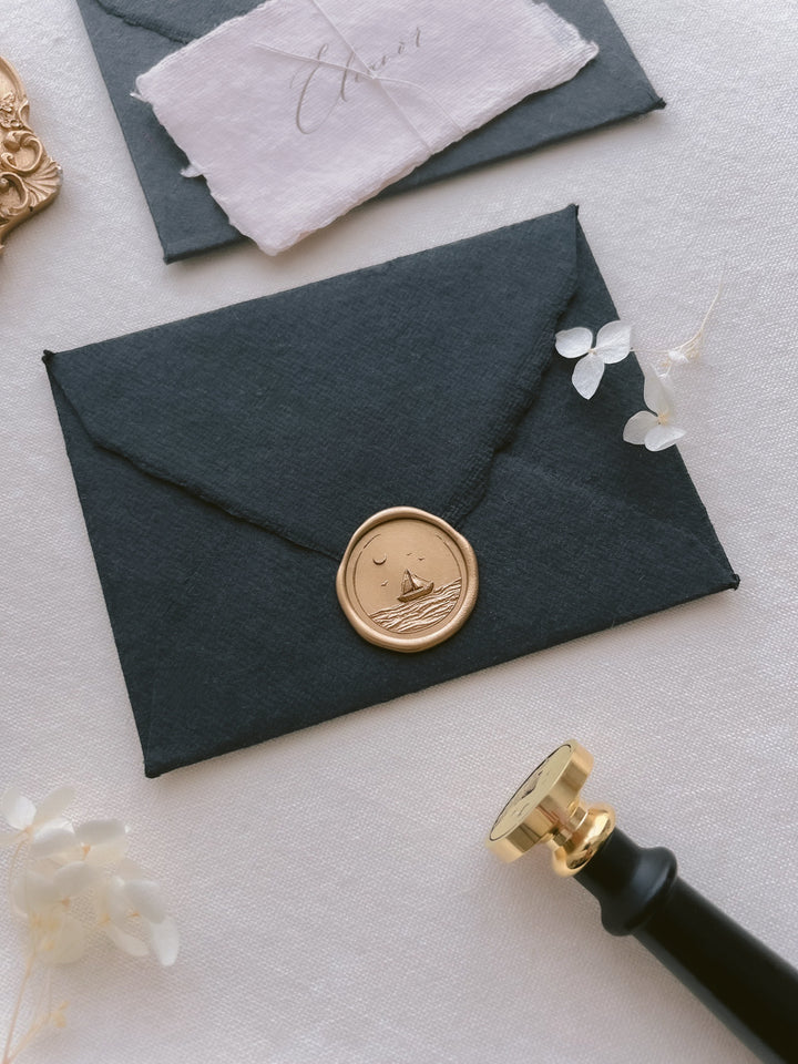 sailboat coastal design gold wax seal on a black envelope 