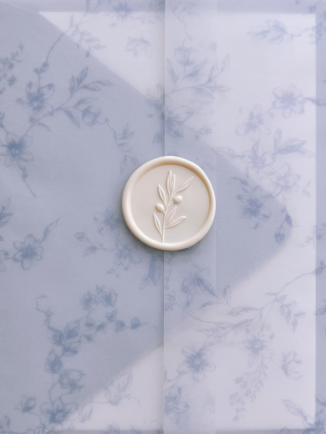 Off-white 3D olive leaf branch wax seal on a blue floral print vellum jacket