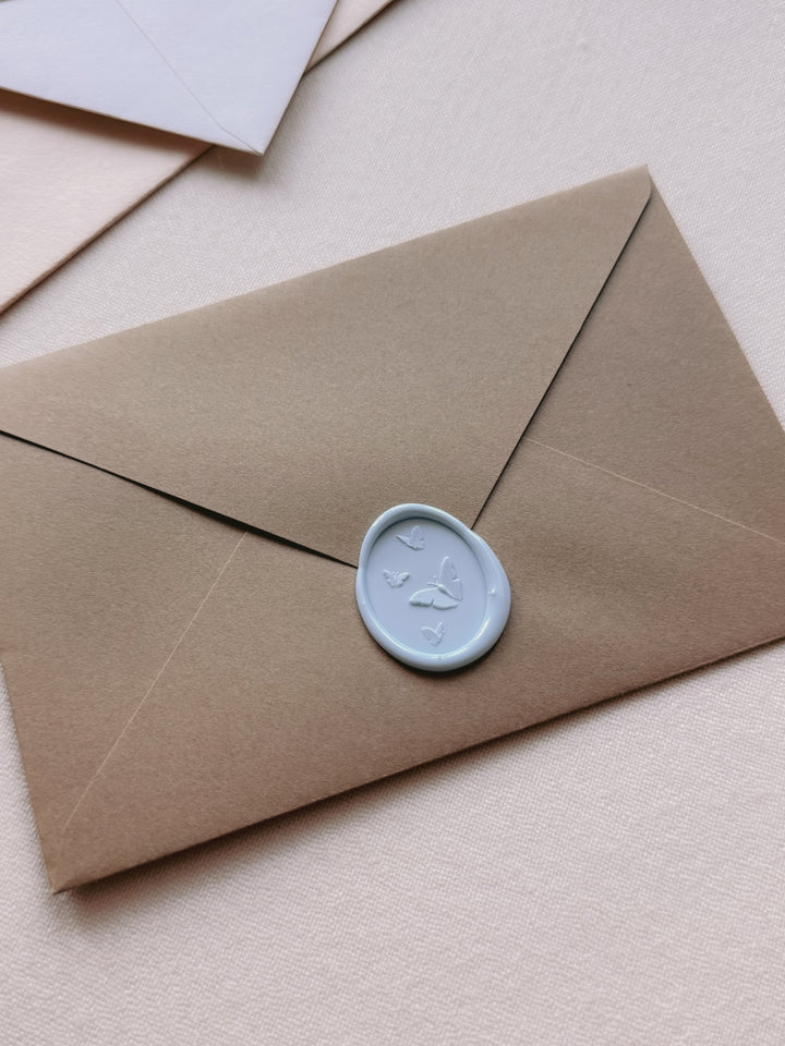 Light blue 3D oval butterflies wax seal on a brown envelope