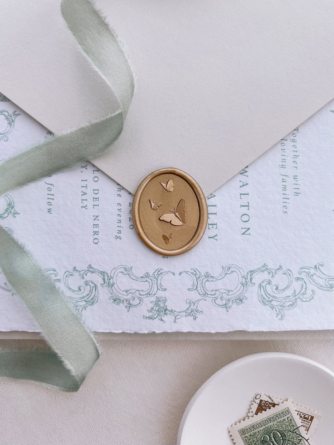 gold 3D oval butterflies wax seal on a cream wedding envelope and sage green ribbon with vintage design