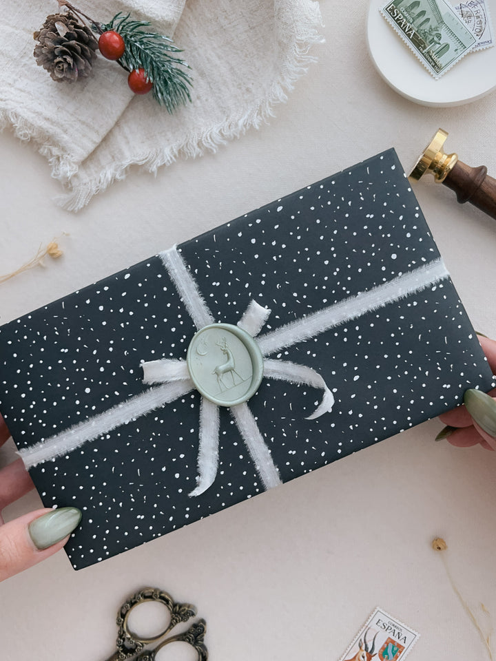 Light metallic sage green 3D reindeer wax seal on a wrapped Christmas gift