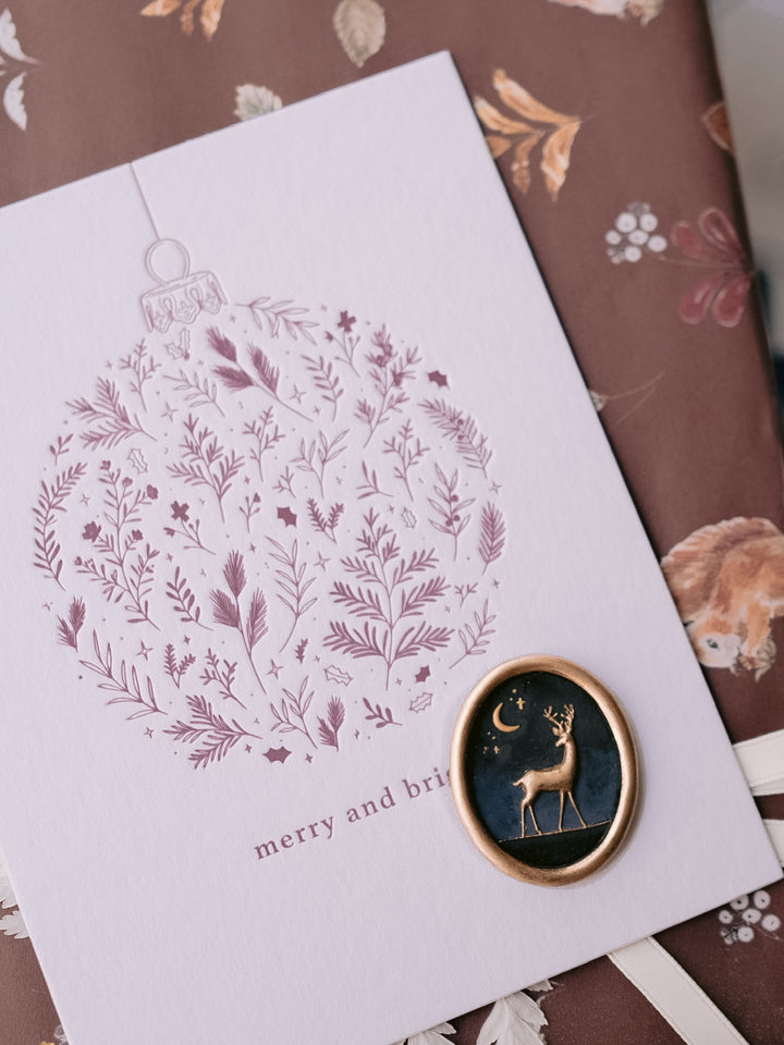 Multi-colored reindeer oval wax seal with a gold edge on a holiday ornament letterpress Christmas card