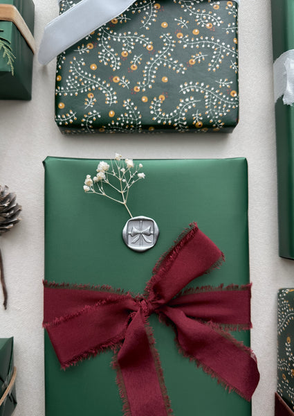 festive gift wrap decorated with silver Christmas bow wax seal 