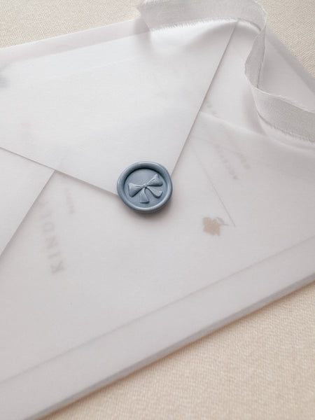 Ribbon bow mini wax seal with 3D engraving in color dusty blue on a vellum envelope