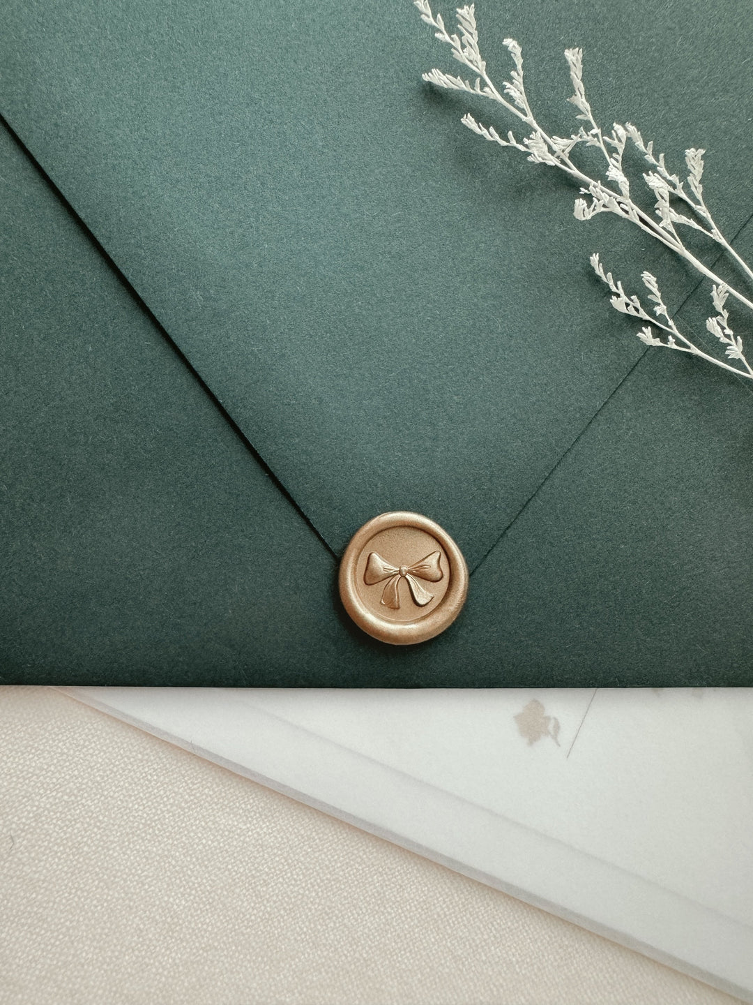Ribbon bow mini wax seal with 3D engraving in color light gold on a dark green envelope