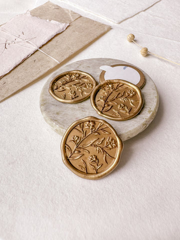 Floral wax seals with 3D engraving in gold styled with a small gray stone dish, handmade paper and a dried floral branch