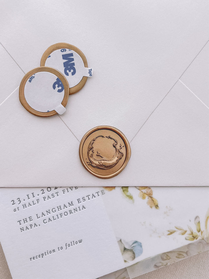 Gold 3D sculpted ocean waves wax seal stickers with self-adhesive backings on a wedding invitation, beige envelope, and vellum jacket