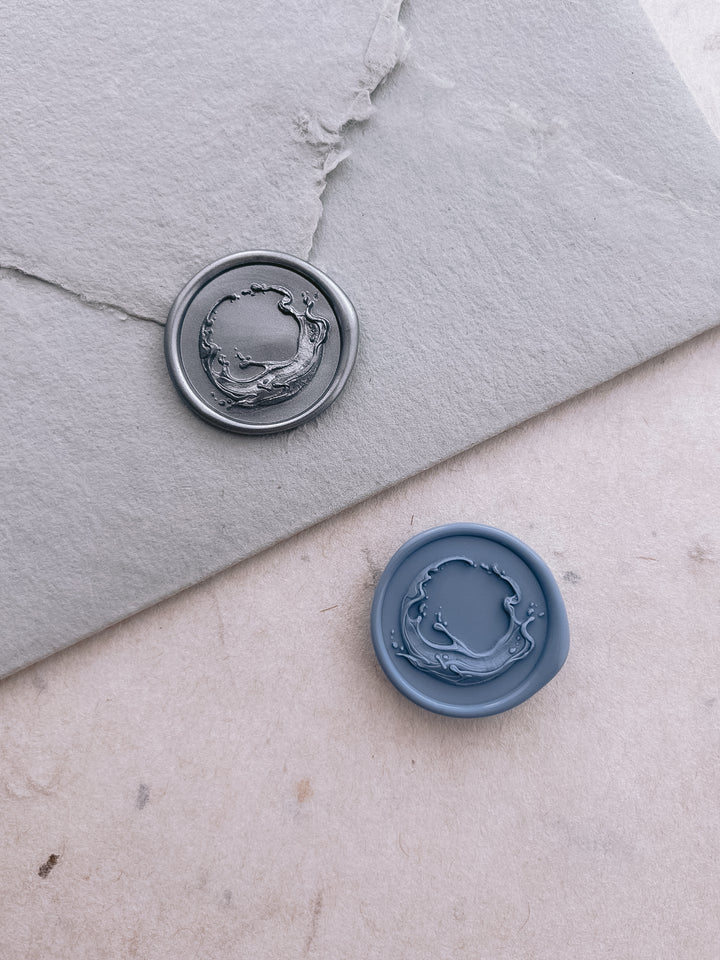 Silver and dusty blue 3D crashing ocean waves wax seals on a light blue envelope and a textured neutral background