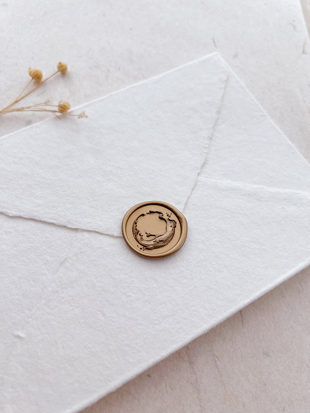Gold 3D sculpted sea wax seal on a white textured handmade paper envelope