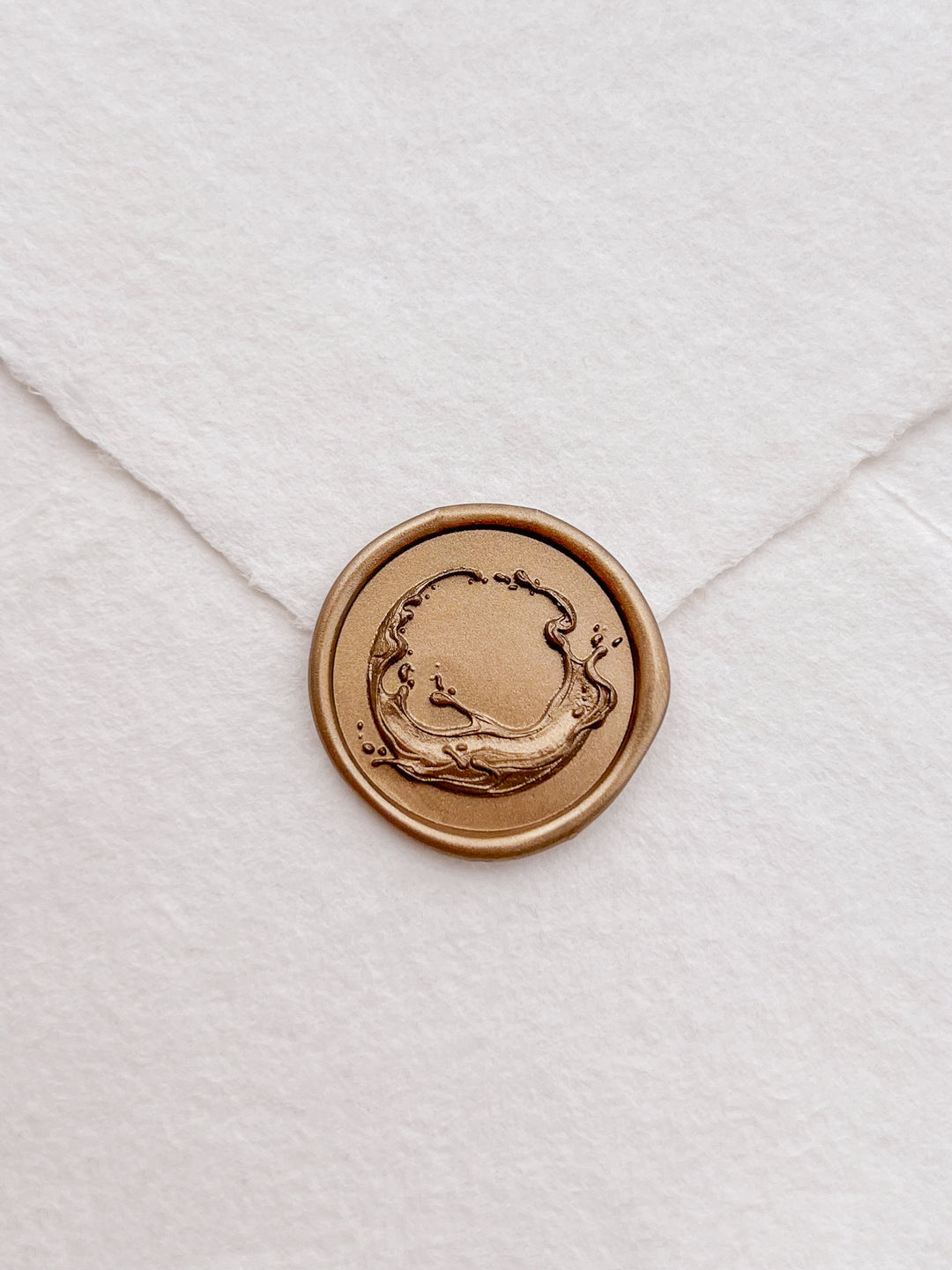 Gold 3D ocean themed wax seal on a white textured handmade paper envelope