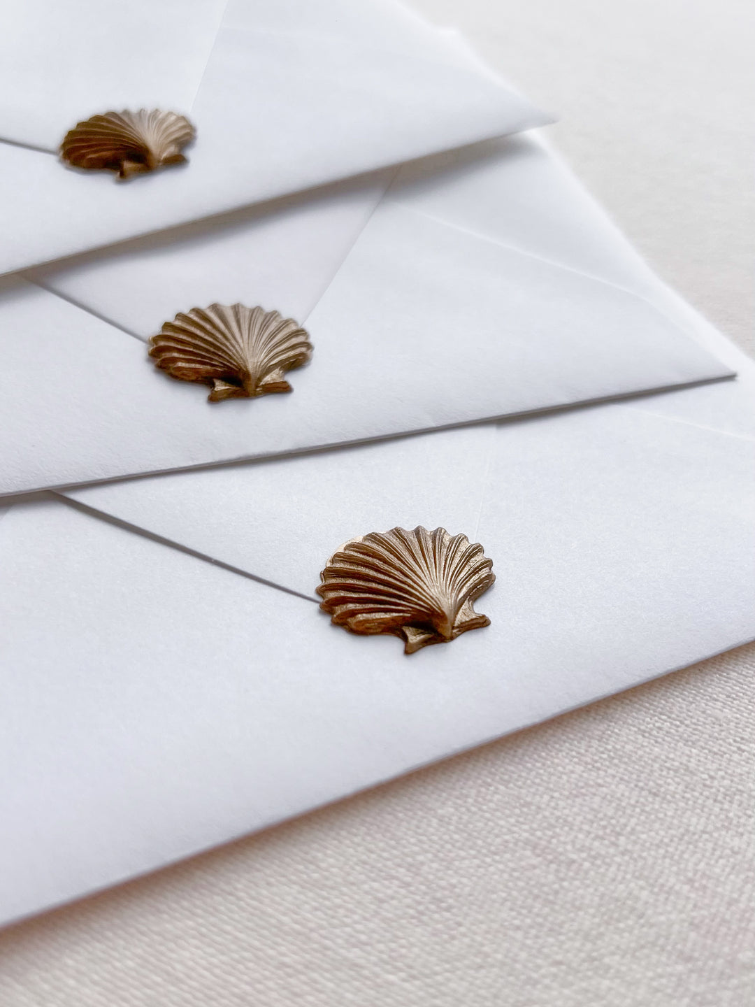 Gold 3D seashell die-cut wax seals on white envelopes 