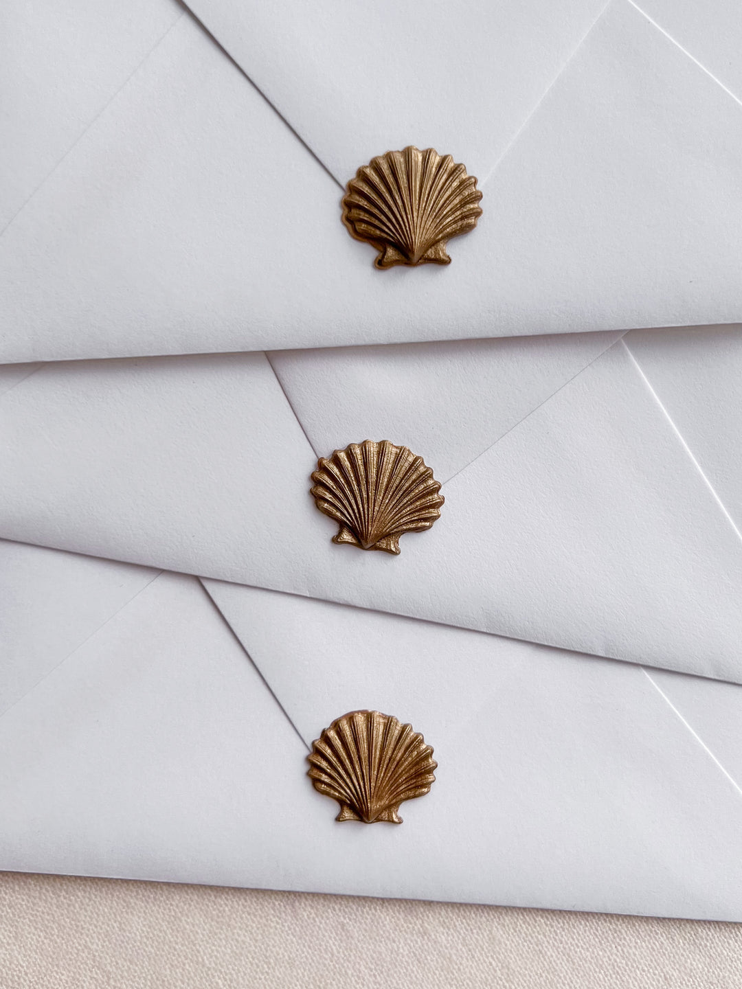 Gold 3D seashell die-cut wax seals on white envelopes 