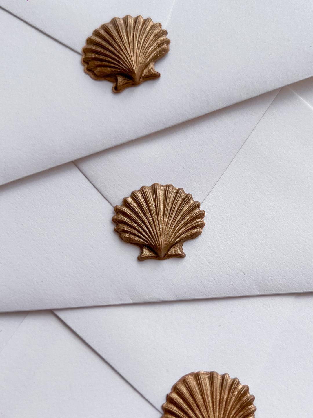 Gold 3D seashell die-cut wax seals on white envelopes 