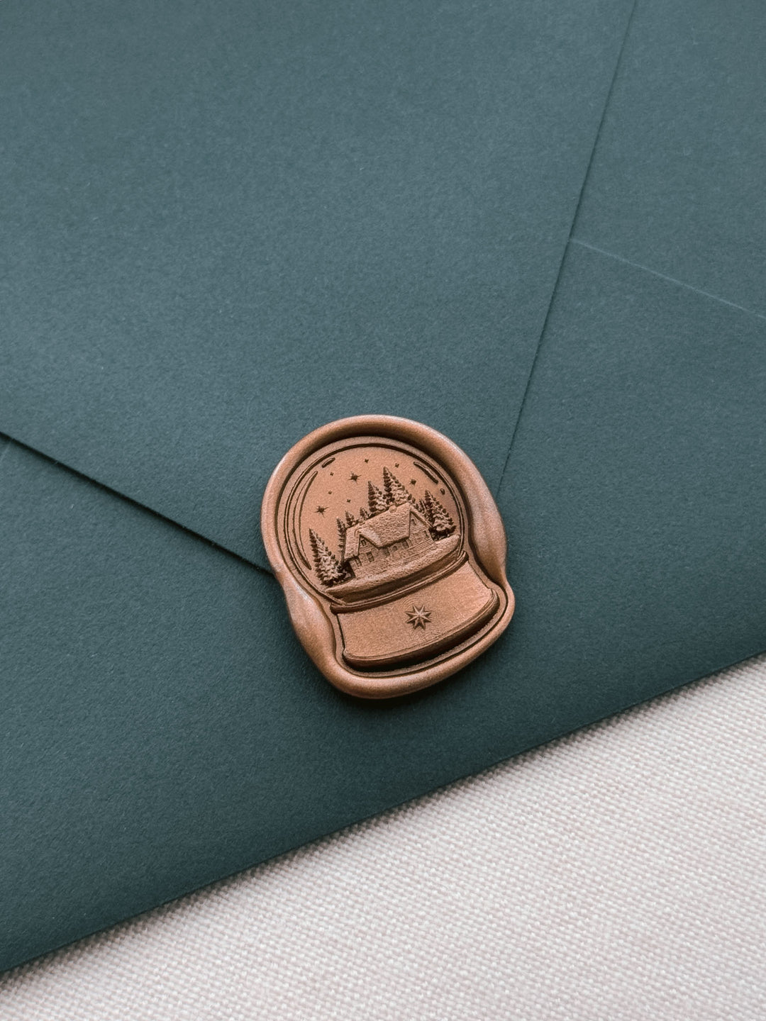 Antique bronze North Star snow globe wax seal on a dark teal envelope 