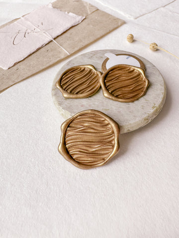 Ocean waves gold wax seals with 3D engraving styled with a small gray stone dish, handmade paper and a dried floral branch