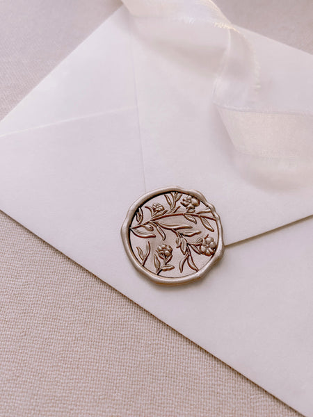 Floral wax seal with 3D engraving in mocha on a white paper envelope styled with a strand of white silk ribbon