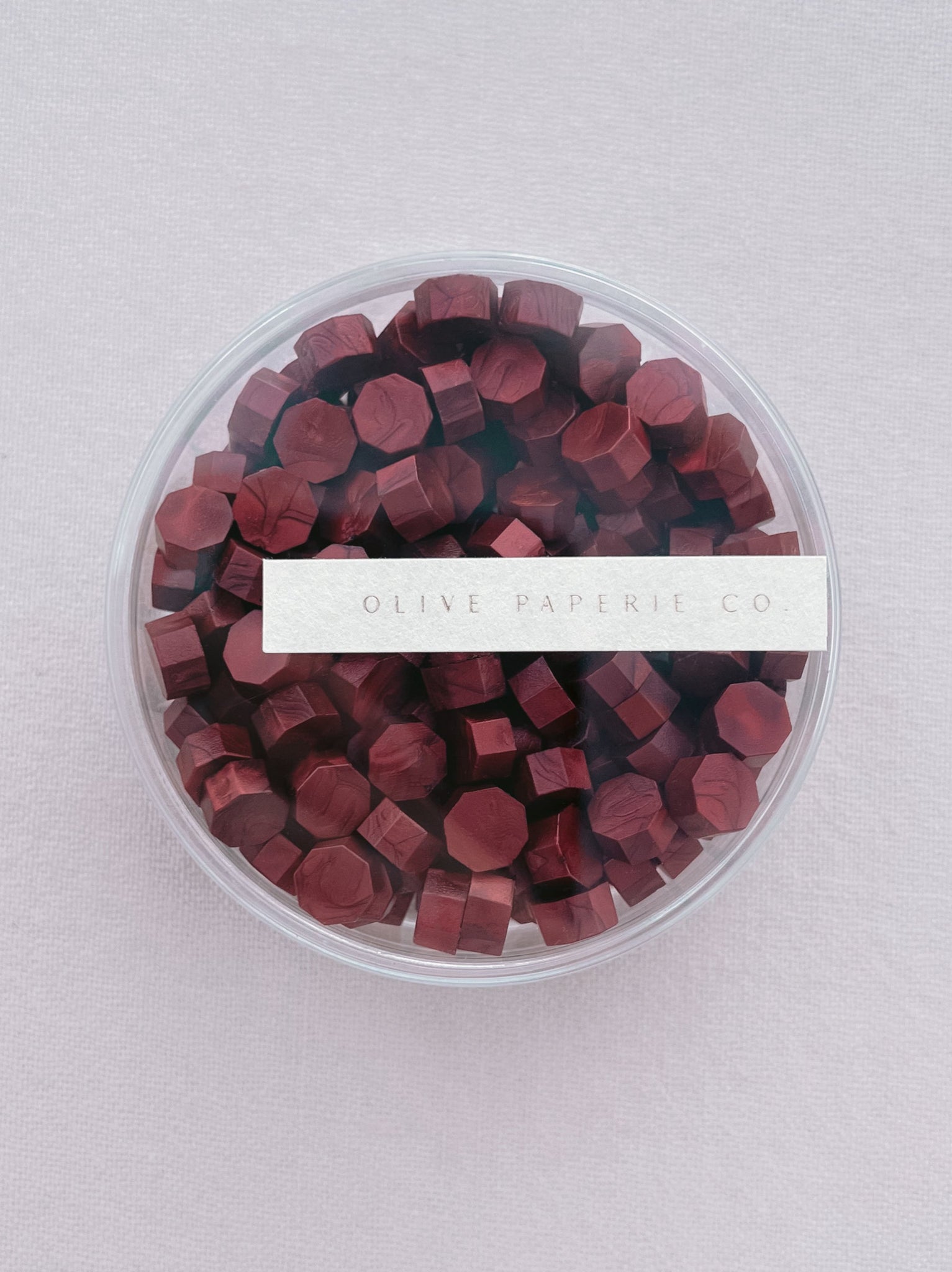 deep metallic red sealing wax beads in a clear round container