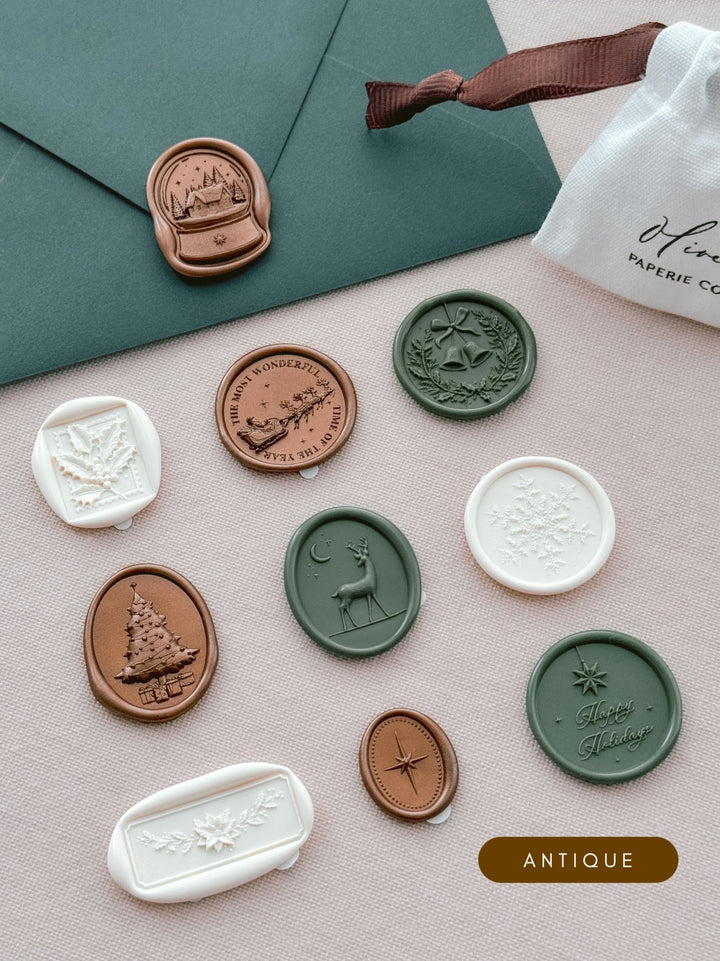 Assorted Christmas wax seal stickers in colors bronze, dark green and antique white in various festive motifs including Christmas wreath, holly, Santa sleigh, reindeer, snow globe, North Star, Christmas tree and more.