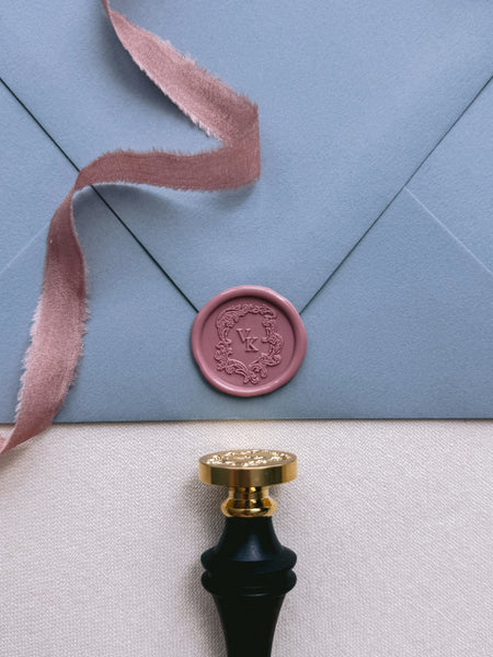 vintage crest personalized initials rose-colored wax seal on dusty blue envelope