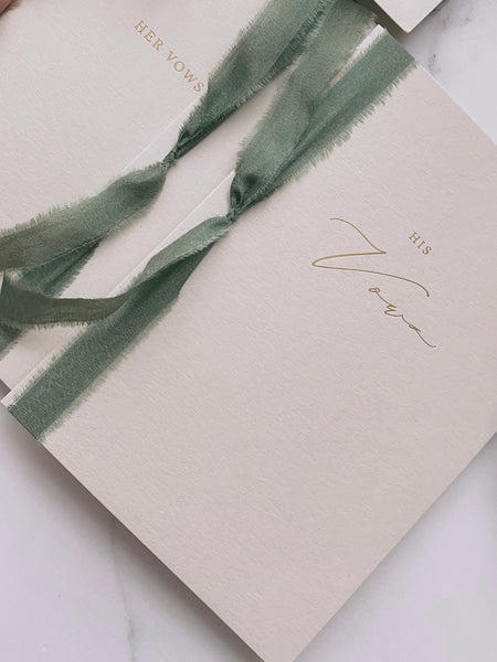A set of two His and Her Vows beige card stock vow books in calligraphy script printed in gold foil tied in olive green colored silk ribbon