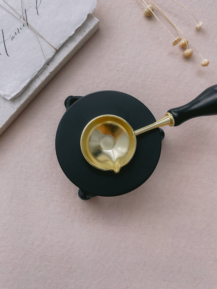 Black color melting stove with gold color melting spoon_top view