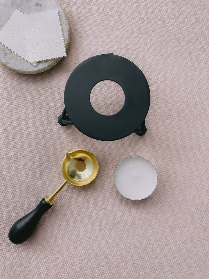 Black color melting stove with gold color melting spoon and white tealight candle