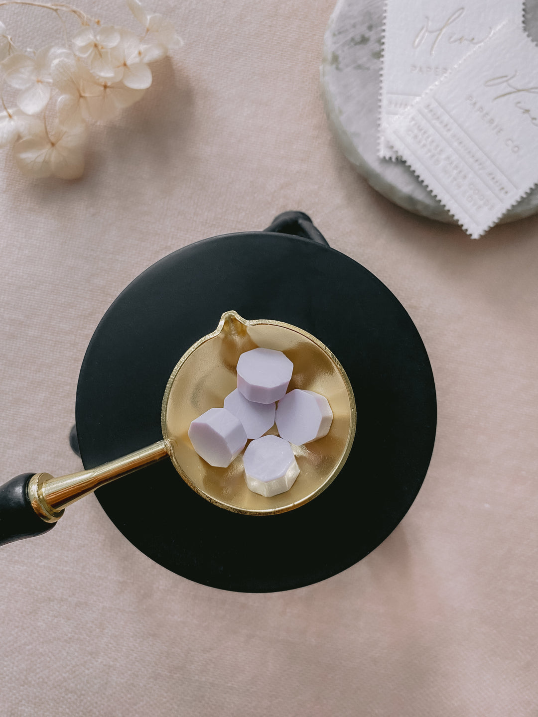 Black color melting stove with wax beads in gold color melting spoon_top view