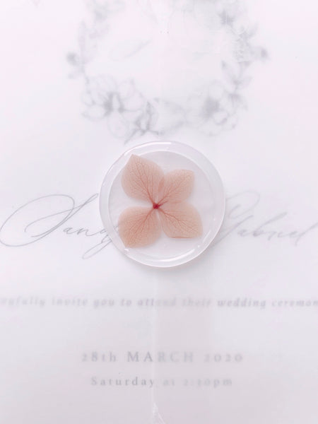 Clear wax seal embellished with blush hydrangea on vellum wrapped wedding invitations