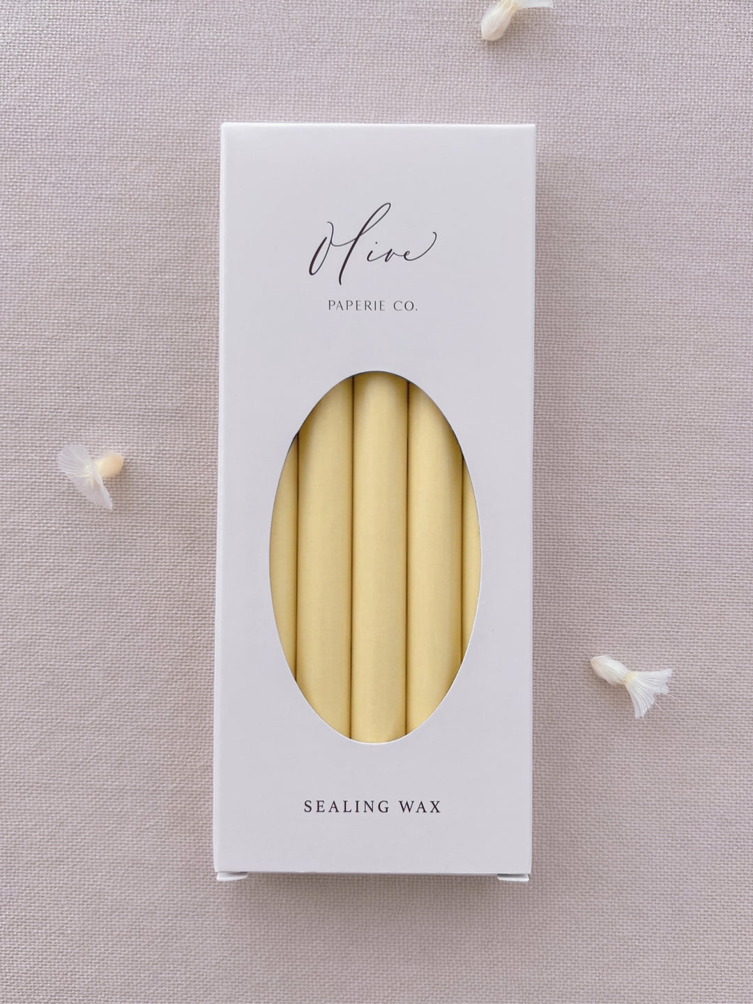 Butter yellow sealing wax sticks in Olive Paperie Co. branded packaging, displayed on a soft linen backdrop with dried flower details.