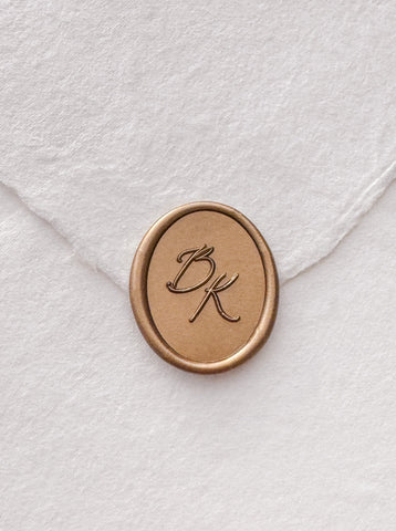 Calligraphy script monogram oval gold wax seal on a white handmade paper envelope