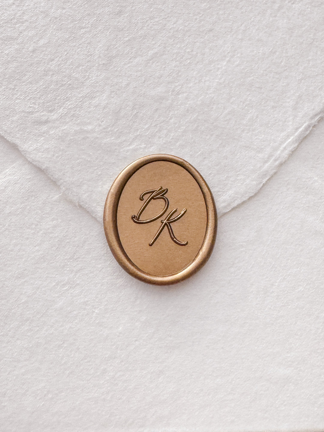Calligraphy script monogram oval gold wax seal on a white handmade paper envelope