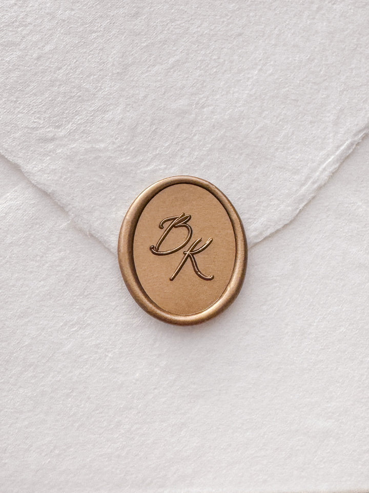 Calligraphy script monogram oval gold wax seal on a white handmade paper envelope