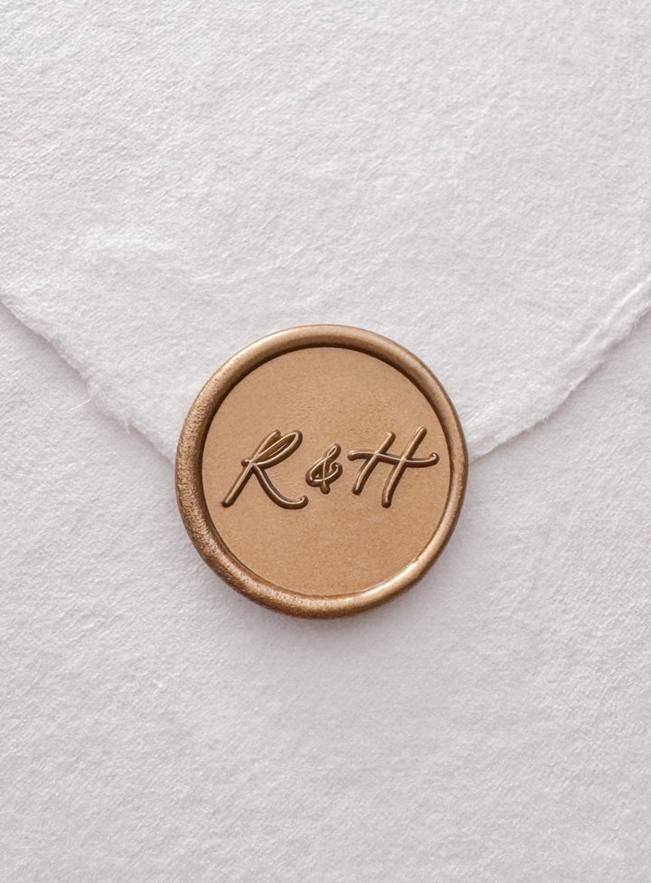 Calligraphy script monogram gold wax seal on a white handmade paper envelope