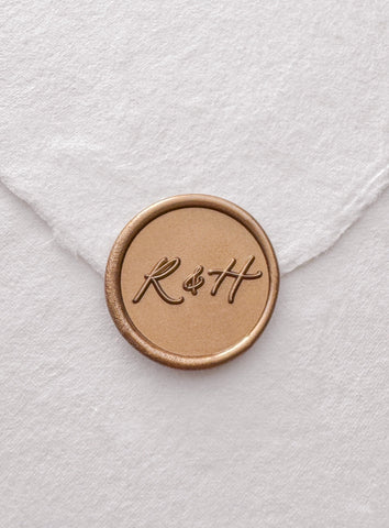 Calligraphy script monogram gold wax seal on a white handmade paper envelope