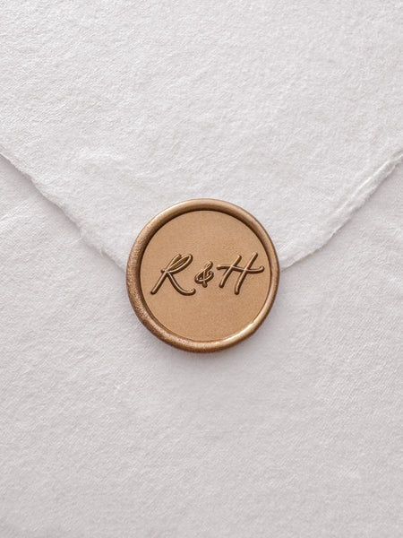 Calligraphy script monogram gold wax seal on a white handmade paper envelope