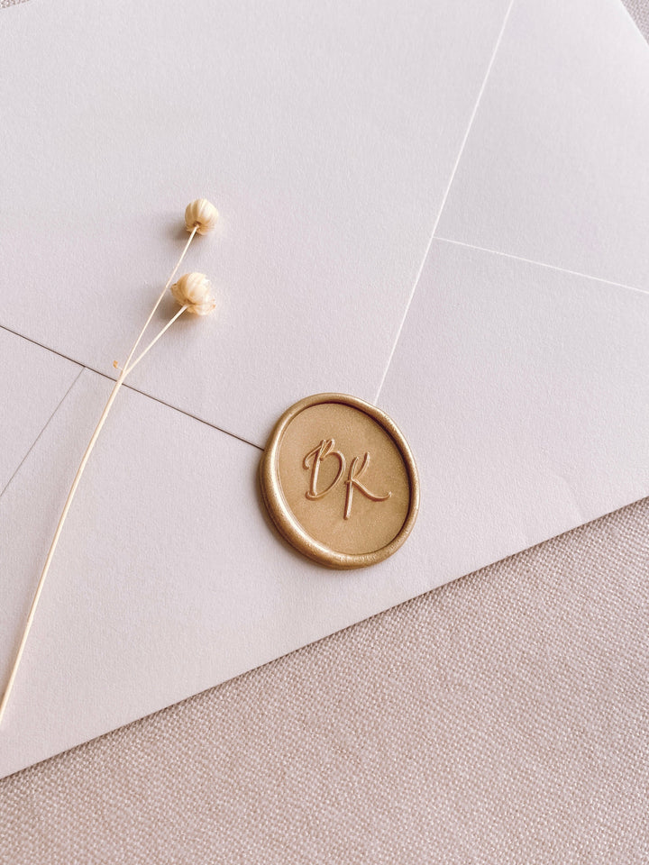 Calligraphy script monogram oval light gold custom wax seal on beige paper envelope
