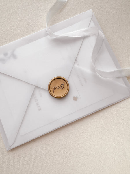 Calligraphy script monogram gold wax seal on a vellum envelope