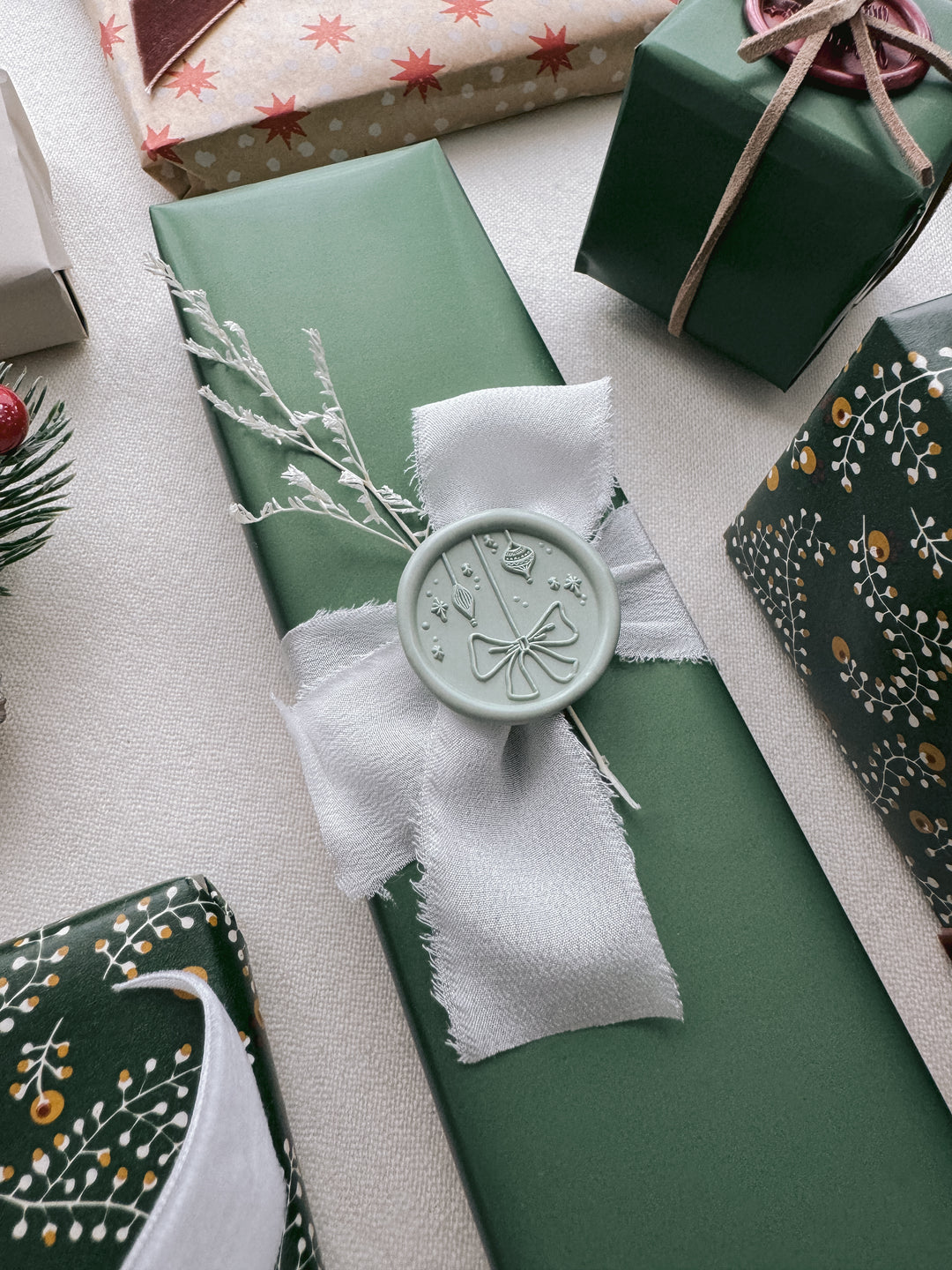 Light sage green festive ornament design wax seal on a wrapped Christmas gift
