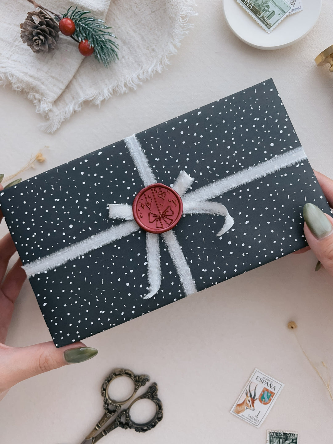 Dark metallic red festive ornament wax seal on a wrapped Christmas gift